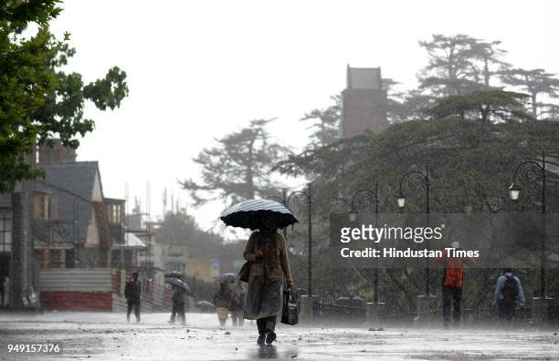 People take a stroll during the wind storm and rain at Ridge on April 20, 2018 in Shimla, India. Shimla and surrounding areas witnessed a severe...