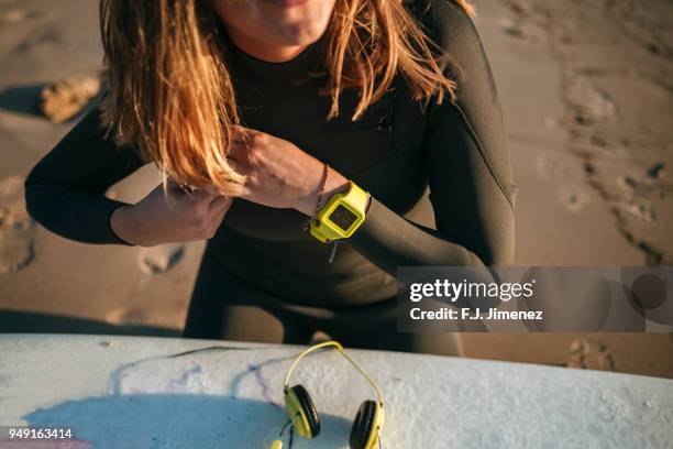 close-up of woman putting on a neoprene in the beach - neoprene stock-fotos und bilder