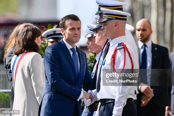 French President Emmanuel Macron shakes hands with police officers flanked by French Interior Minister Gerard Collomb during a ceremony, on April 20...