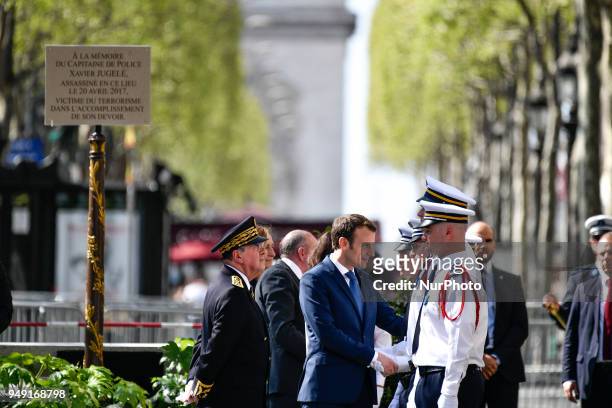 French President Emmanuel Macron shakes hands with police officers flanked by French Interior Minister Gerard Collomb during a ceremony, on April 20...