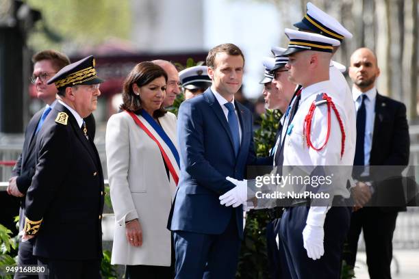 French President Emmanuel Macron shakes hands with police officers flanked by French Interior Minister Gerard Collomb during a ceremony, on April 20...