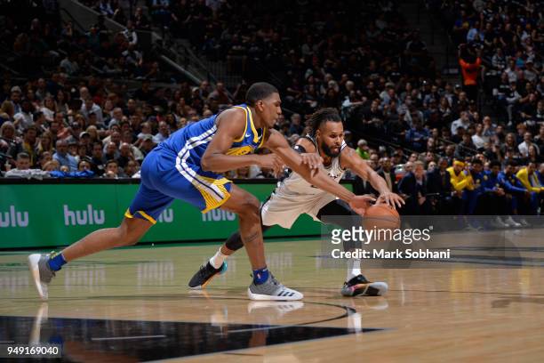 Kevon Looney of the Golden State Warriors and Patty Mills of the San Antonio Spurs go for a loose ball during Game Three of the Western Conference...