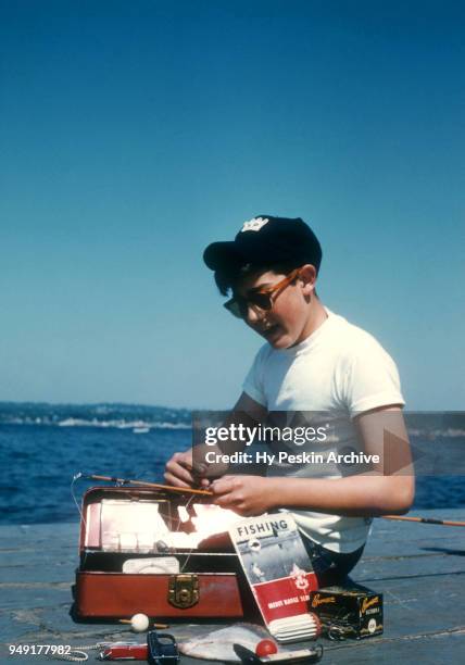 Young boy grabs a bobber from his tackle box to add to his fishing line circa 1960's.