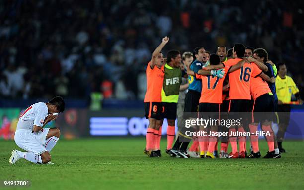 Faustino Rojo of Estudiantes kneels dejectedly while Barcelona players celebrate their victory at the end of the Club World Cup Final match between...