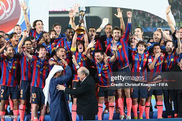 Carlos Puyol holds the cup aloft amongst FC Barcelona players after it was presented by FIFA president Joseph Blatter and Mohammed Khalfan...