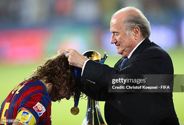 President Joseph Blatter presents a gold medal to Carlos Puyol of Barcelona after the FIFA Club World Cup Final match between Estudiantes LP and FC...