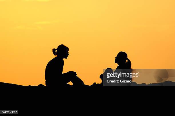 two women having a friendly chat outside - engaged sunset stockfoto's en -beelden