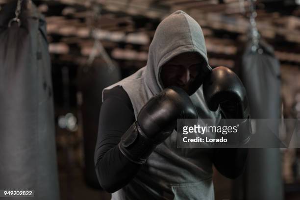 middle aged redhead handsome boxer fighter training with heavy bag in gym setting - mixed martial arts stock pictures, royalty-free photos & images