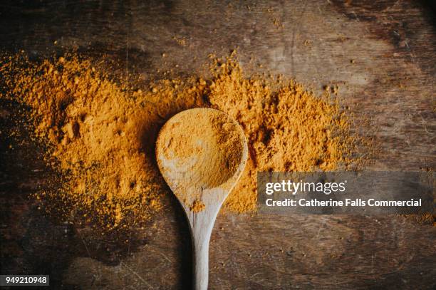 turmeric powder on a wooden spoon - orange powder ストックフォトと画像