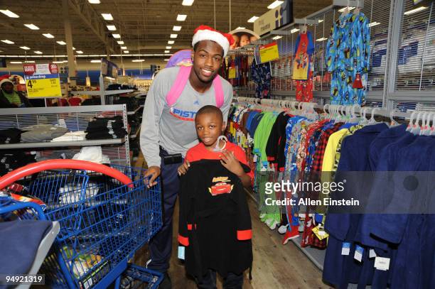 Rodney Stuckey of the Detroit Pistons helps with a child choose a new bath robe for Christmas during Rip Hamilton's annual holiday shopping spree for...