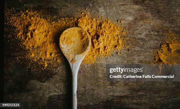 turmeric powder on a wooden spoon - chilli powder imagens e fotografias de stock