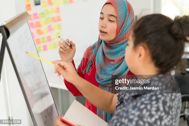 muslim girl and boy studying at home on whiteboard - two young arabic children only indoor portrait stock pictures, royalty-free photos & images