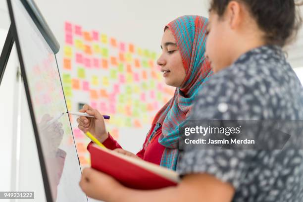 muslim girl and boy studying at home on whiteboard - two young arabic children only indoor portrait stock pictures, royalty-free photos & images