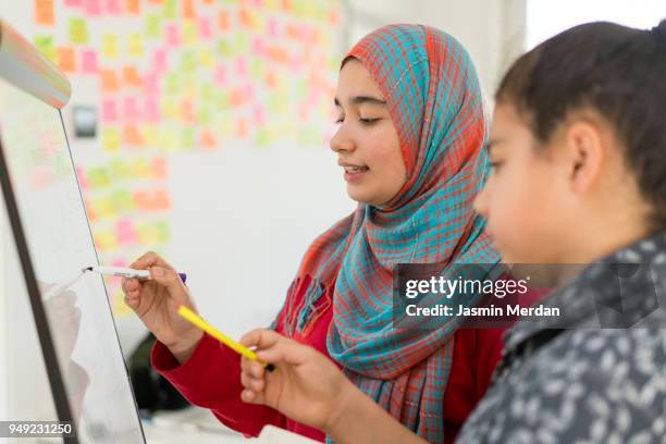 muslim girl and boy studying at home on whiteboard - two young arabic children only indoor portrait stock pictures, royalty-free photos & images