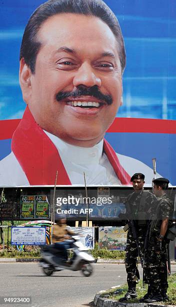 Sri Lankan special forces commandos stands guard near a campaign poster of Sri Lankan President Mahinda Rajapakse in Colombo on December 20, 2009....