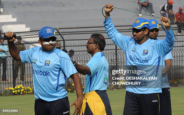 Sri Lankan cricketers Tillakaratne Dilshan and Mahela Jayawardene stretch during a practice session at the Barabati Stadium in Cuttack on December 20...