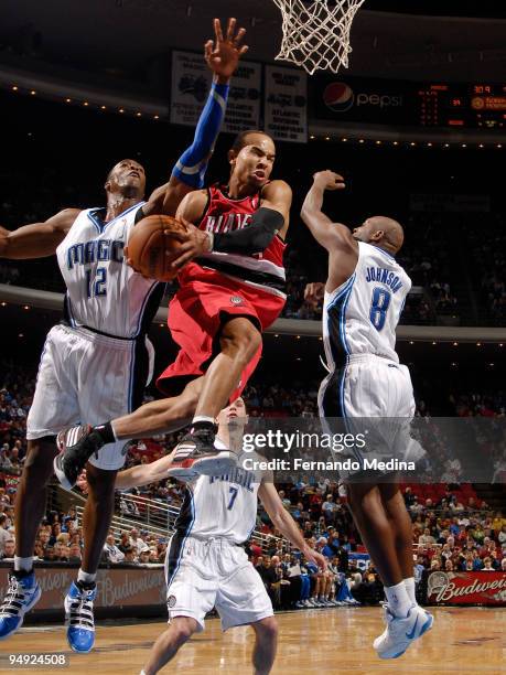 Jerryd Bayless of the Portland Trail Blazers moves the ball between Dwight Howard and Anthony Johnson of the Orlando Magic in the lane during the...