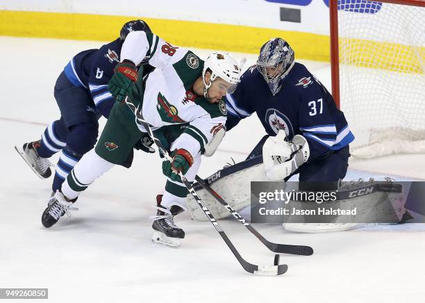 Connor Hellebuyck of the Winnipeg Jets makes a save off Jordan Greenway of the Minnesota Wild in Game Five of the Western Conference First Round...