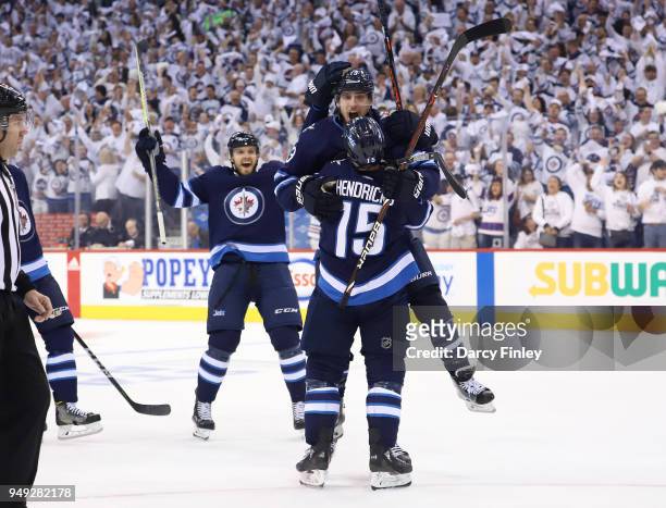 Ben Chiarot of the Winnipeg Jets joins teammates Brandon Tanev and Matt Hendricks as they celebrate a first period goal against the Minnesota Wild in...