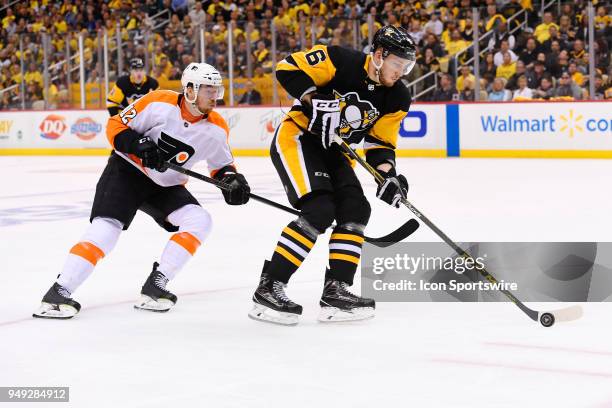 Pittsburgh Penguins defenseman Jamie Oleksiak skates with the puck while Philadelphia Flyers left wing Michael Raffl forechecks during the third...