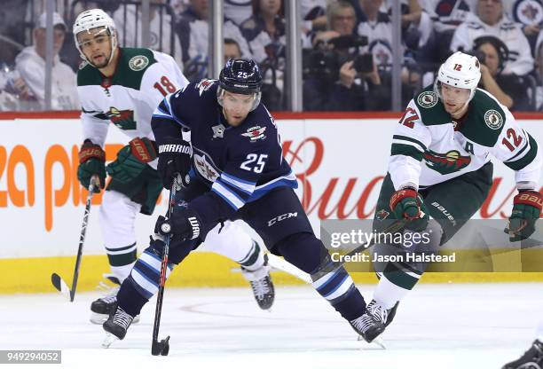 Paul Stastny of the Winnipeg Jets moves the puck under pressure from Eric Staal and Jordan Greenway of the Minnesota Wild in Game Five of the Western...