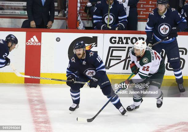 Bryan Little of the Winnipeg Jets and Nino Niederreiter of the Minnesota Wild chase an airborne puck in Game Five of the Western Conference First...