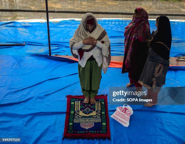 Kashmiri Muslim woman devotee prays inside the compound of Hazratbal Shrine. Despite incessant rainfall, thousands of devotees from across the...