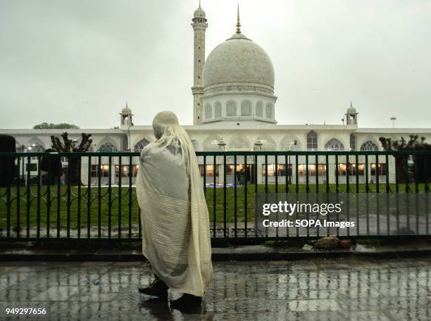 Kashmiri Muslim woman devotee walks inside the compound of Hazratbal Shrine. Despite incessant rainfall, thousands of devotees from across the...