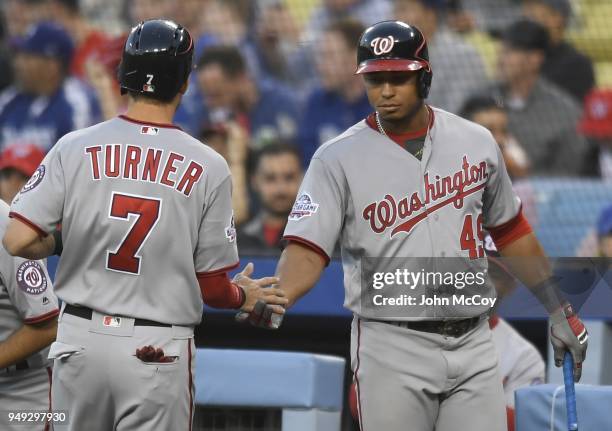 Trea Turner of the Washington Nationals is welcomed into the dugout by Moises Sierra of the Washington Nationals after scoring in the first inning...