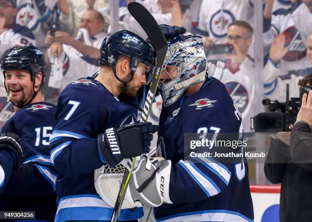 Ben Chiarot of the Winnipeg Jets congratulates goaltender Connor Hellebuyck following a 5-0 shutout over the Minnesota Wild in Game Five of the...