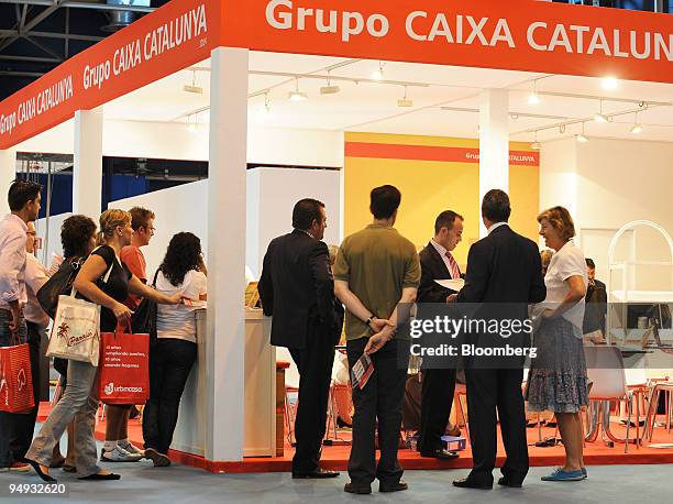 Visitors look at the property display on the Grupo Caixa Catalunya stand during the retail housing fair in Madrid, Spain, on Friday, Sept. 12, 2009....