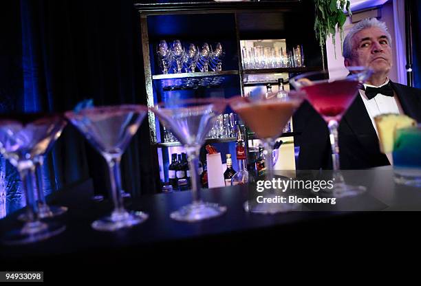 Bartender stands at a booth displaying red, white and blue drinks at a trade show featuring goods and services available to hotel guests during the...
