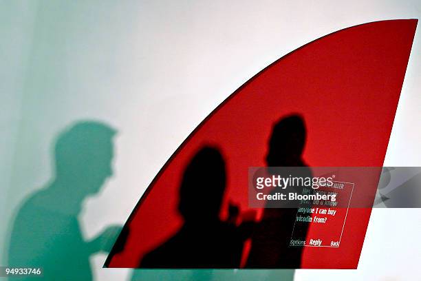 The shadows of three attendees are projected on a work by Adam McEwen on display at The Station in Miami, Florida, U.S., on Tuesday, Dec. 2, 2008....