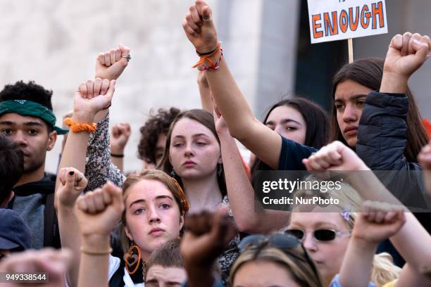 Students raise their fists during a moment of silence for gun violence victims during the National School Walkout in Los Angeles, California on April...