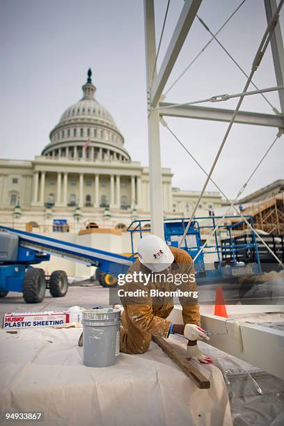 Worker paints part of the platform being constructed on the west front of the U.S. Capitol in preparation for the inauguration ceremony of incoming...