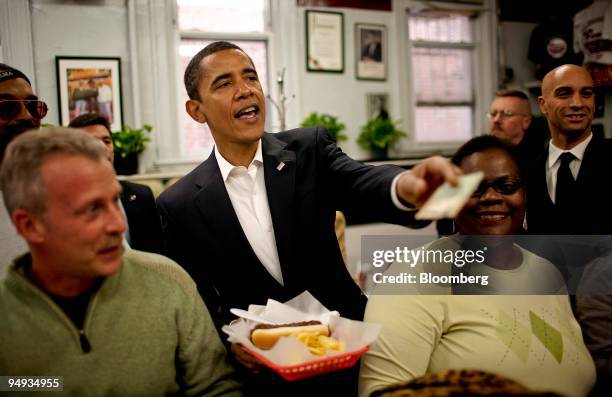 President-elect Barack Obama, center, pays for a chili half smoke with a side of shredded cheese at Ben's Chili Bowl in Washington, D.C., U.S., on...
