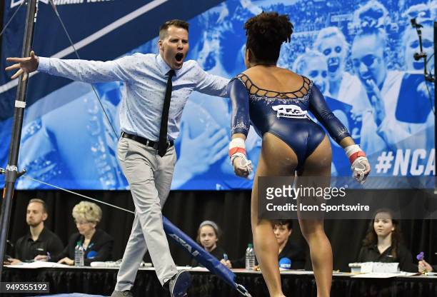 Associate head coach Chris Waller greets Savannah Kooyman of UCLA after she finished the bars during the NCAA Women's Gymnastics National...