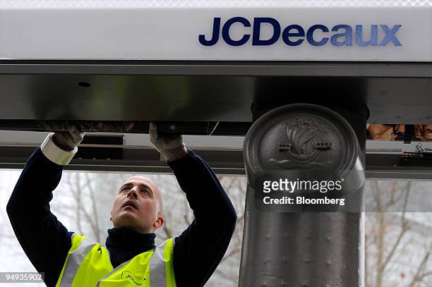 Frederic Cardon, a JCDecaux employee, changes an advertising poster in Paris, France, on Wednesday, Jan. 22, 2009. The company releases its earnings...