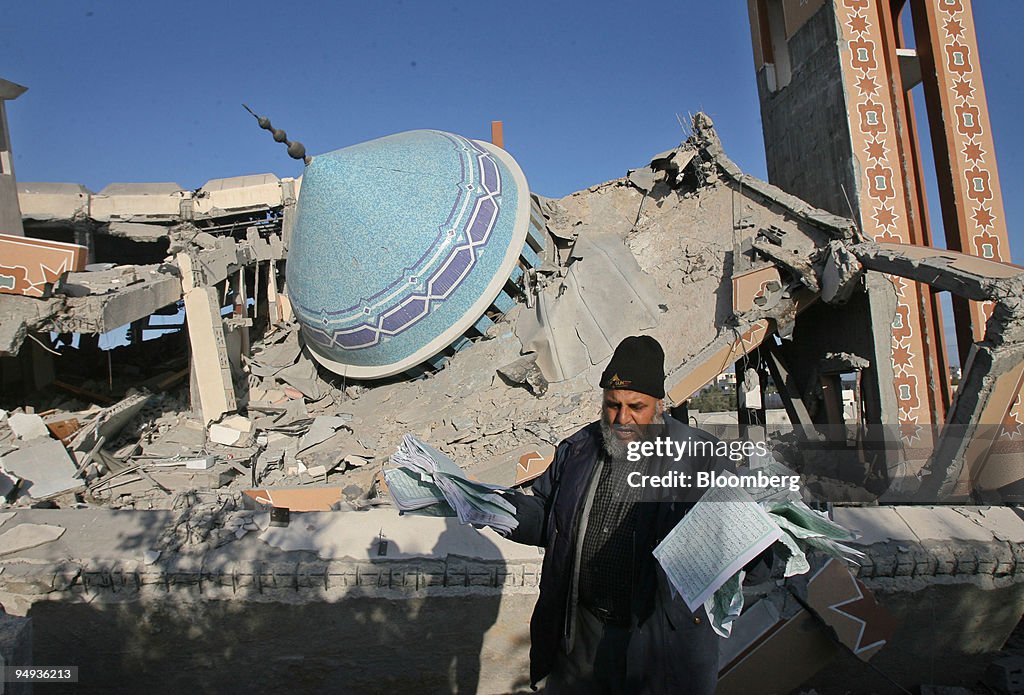 A Palestinian collects pages of a Koran from the rubble of t