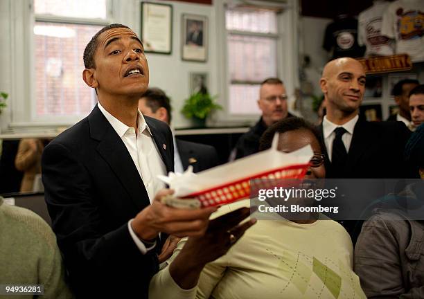 President-elect Barack Obama, left, receives a chili half smoke with a side of shredded cheese at Ben's Chili Bowl in Washington, D.C., U.S., on...