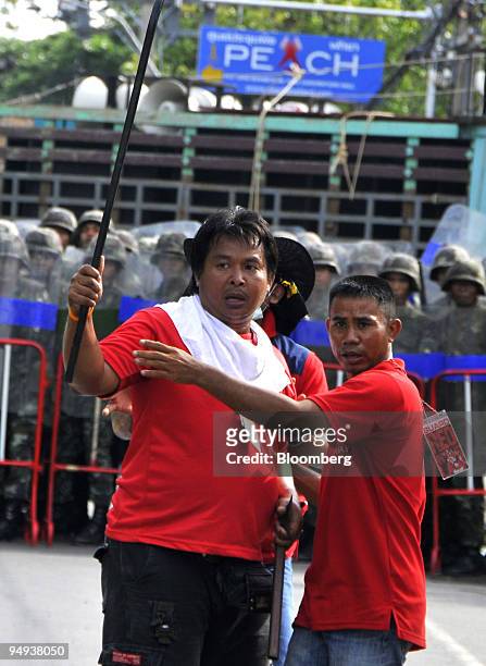 Anti-government red-shirted protesters armed with metal bars assemble near a cordon of soldiers as they march on the venue of the Association of...