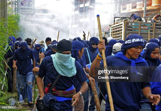 Handgun is held above pro-government blue-shirted protesters armed with sticks near the venue of the Association of Southeast Asian Nations plus...