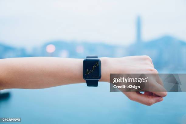 financial trading data shown on smart watch on human hand against urban city skyline - orologio da polso foto e immagini stock