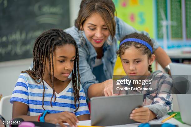 leraar helpen kinderen - school tablet stockfoto's en -beelden