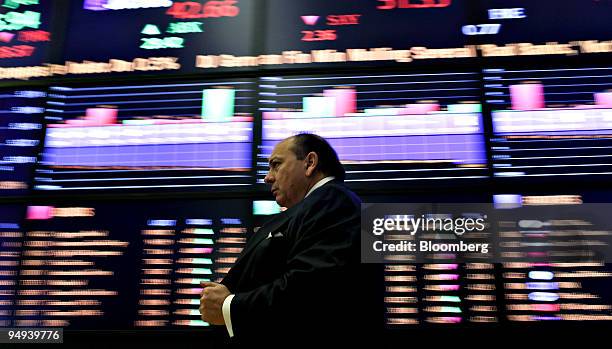 Man walks past screens displaying market data on the floor of the New York Stock Exchange in New York, U.S., on Monday, April 13, 2009. U.S. Stocks...