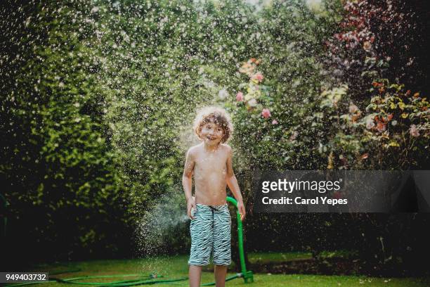 boy  playing sprinkler - wet hose ストックフォトと画像