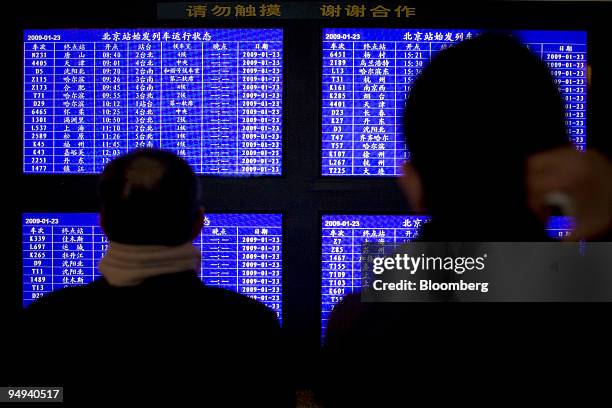 Passengers and migrant workers returning home for the Chinese Lunar New Year check the train schedule at Beijing Railway Station, in China, on...