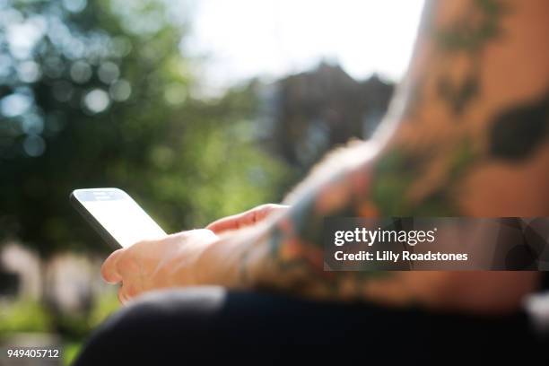 man with tattoos using mobile phone - lilly roadstones stock pictures, royalty-free photos & images