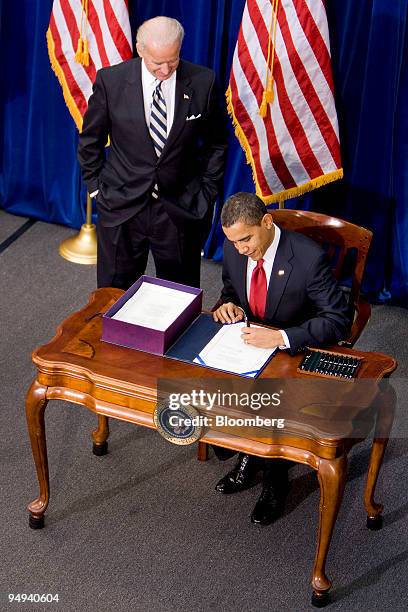 Vice President Joe Biden, left, looks on as U.S. President Barack Obama signs an economic stimulus package into law inside the Museum of Nature and...