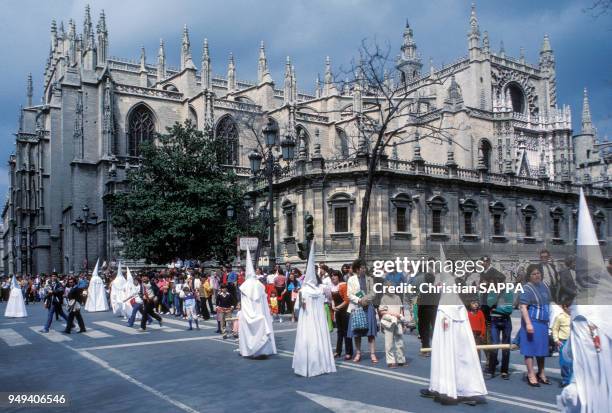 Procession de pénitents pendant la semaine sainte devant la cathédrale Notre-Dame du Siège à Séville, en Andalousie, Espagne.